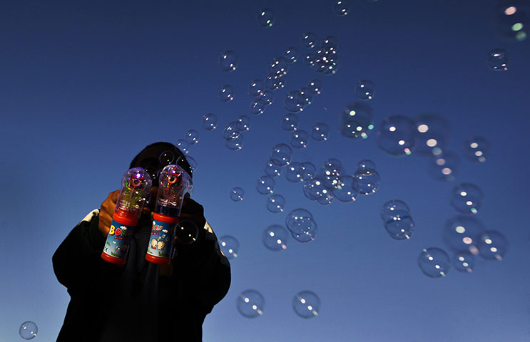 24 hours in pictures: Tripoli, Libya: A man makes bubbles with two electric bubble-blowers