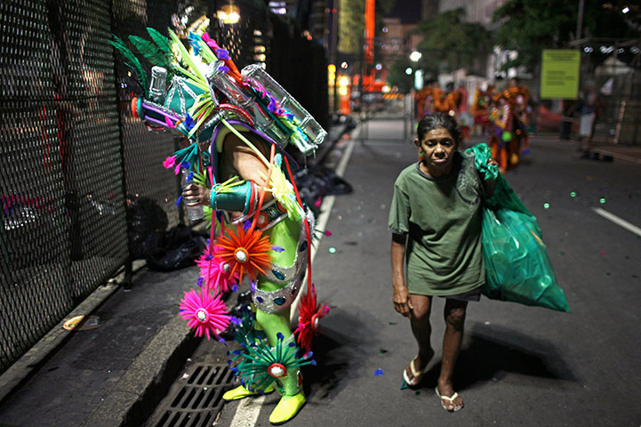 24 hours in pictures: Rio de Janeiro, Brazil: A trash collector walks past a reveller