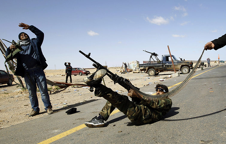 Libya battles continue: A rebel fighter fires his rifle at a military aircraft at Ras Lanuf