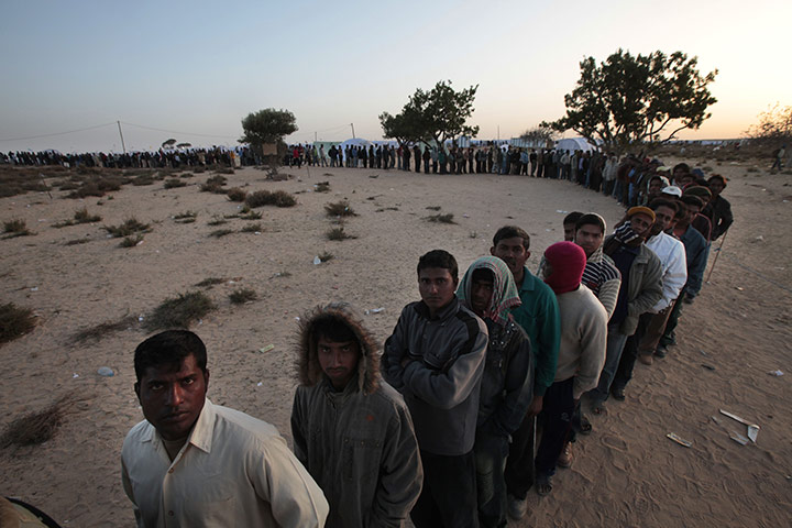 Libya battles continue: Men from Bangladesh wait in line for food in a refugee camp at the border