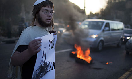A man holds a sign in support of settlers living in the Havat Gilad outpost