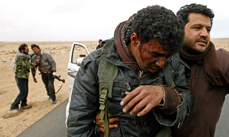 Injured rebels are helped out of a car during a battle between Ras Lanuf and Bin Jiwad, Libya 