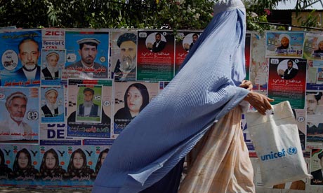 An Afghan woman walks past the election posters of parliamentary candidates in Jalalabad, July 2010