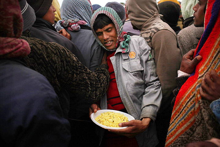 Libya Ras Jdir: A Bangladeshi man walks through a line with his food at a camp in Ras Jdir