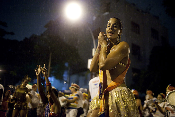 from the agencies : A people dance in the rain during a street carnival parade