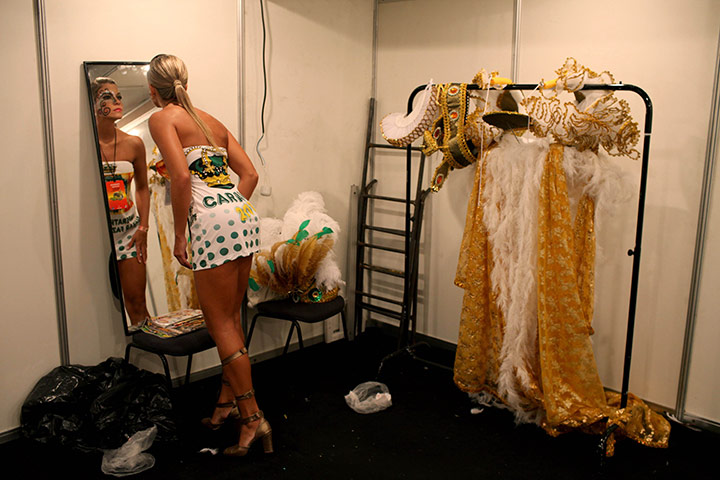from the agencies : A woman looks in the mirror as prepares for Sunday's carnival parade