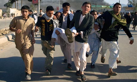 Afghans carrying a man wounded in the outbreak of violence at Mazar-e-Sharif