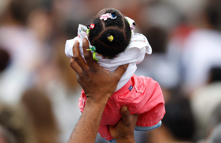 24 hours in pictures: A man raises a baby during Pope Benedict XVI's blessing at the Vatican