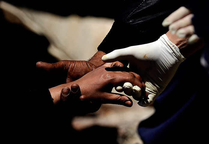 24 hours in pictures: Migrants are helped by policemen as they disembark from a boat, Italy