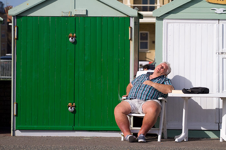 UK weather: A man asleep outside beach hut on the seafront, Hove