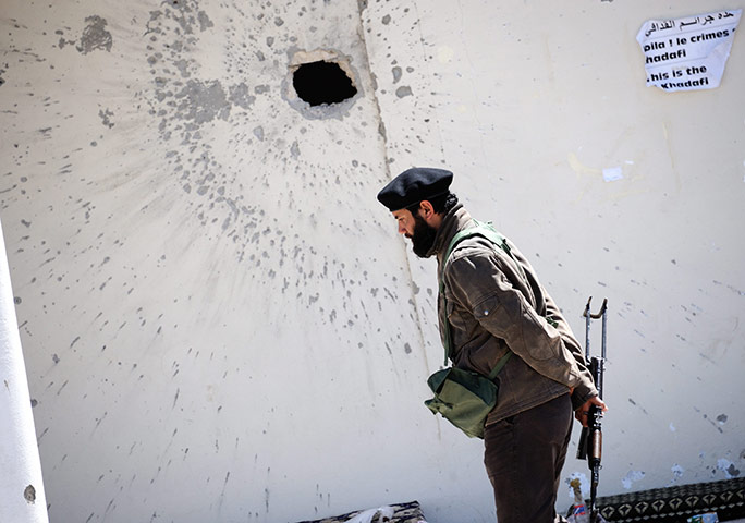 24 hours: Ajdabiya, Libya: A rebel fighter stands in front of a bullet hole in a wall