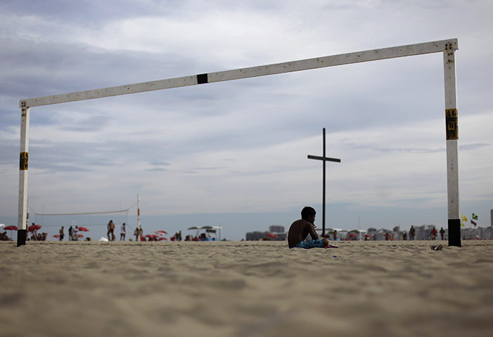 24 hours: Rio de Janeiro, Brazil: A boy sits near a cross on Copacabana Beach