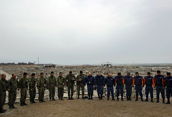 Japan disaster 1 month on: Rescue workers observe a minute silence in  in Natori, Miyagi Prefecture 