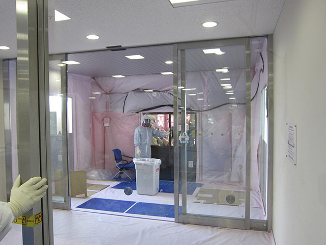 Fukushima disaster: 31 March: A worker in a protective suit installs the de-contamination area