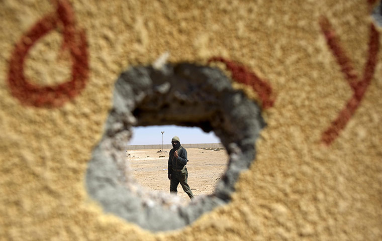 Ajdabiya, Libya : A rebel soldier is seen through a hole in a concrete wall, Ajdabiya