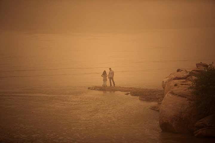 24 hours in pictures: An Iranian couple stand on the shore of the Arvandrud river
