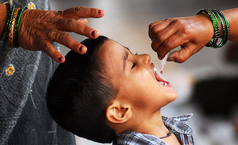 Week in Business: An Indian health worker gives a Polio vaccination to a child