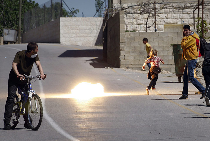 24 Hours in Pictures: A demonstrator runs away from tear gas fired by Israeli soldiers