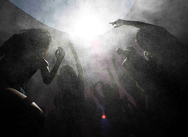 24 Hours in Pictures: Concert goers move in a spray of cooling mist at the Coachella Festival