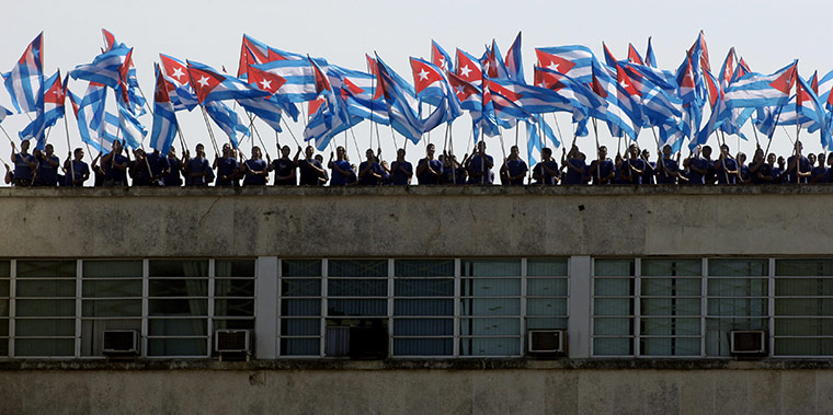 Bay of Pigs anniversary: People wave Cuban flags on a roof during a military parade