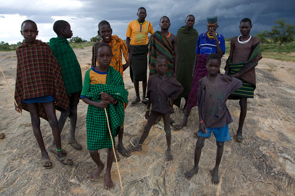 Karamojong youth stand on a rock outcrop outside Kotido