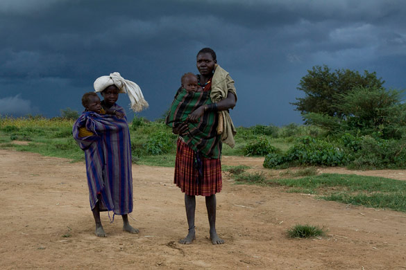 Karamojong women carry babies outside Kotido