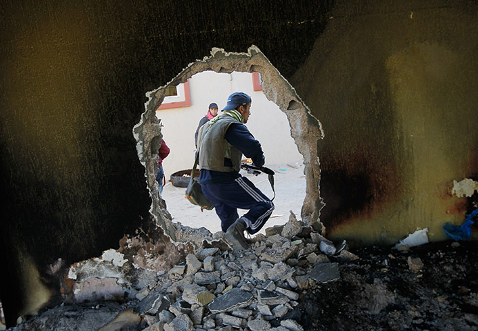  Misrata, Libya : A rebel fighter moves through a hole punched in a wall near the front line