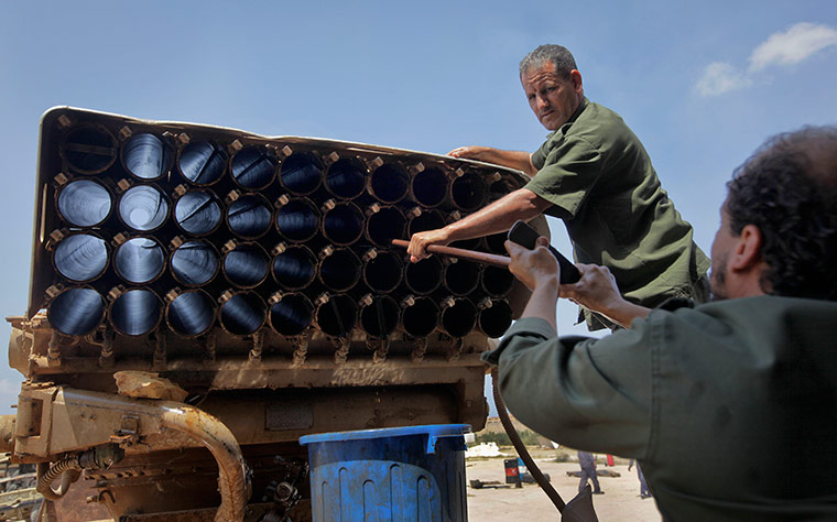 Libyan rebel workshop: Workmen clean a rusted Grad rocket 