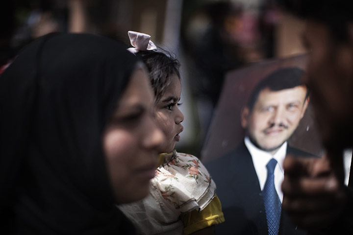 24 Hours in pictures: A Jordanian protester walks past a portrait of King Abdullah II