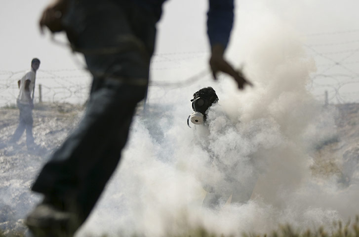 24 Hours in pictures: Palestinians demonstrators run away from tear gas fired by Israeli troops