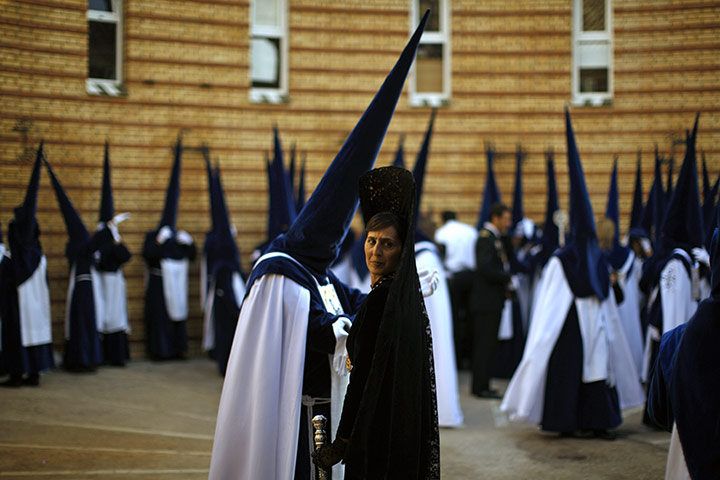 Holy Week in Malaga: Penitents and a woman wearing a traditional mantilla