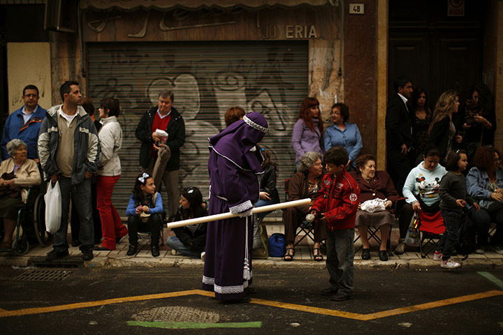 Holy Week in Malaga: A penitent gives wax of a candle to a child