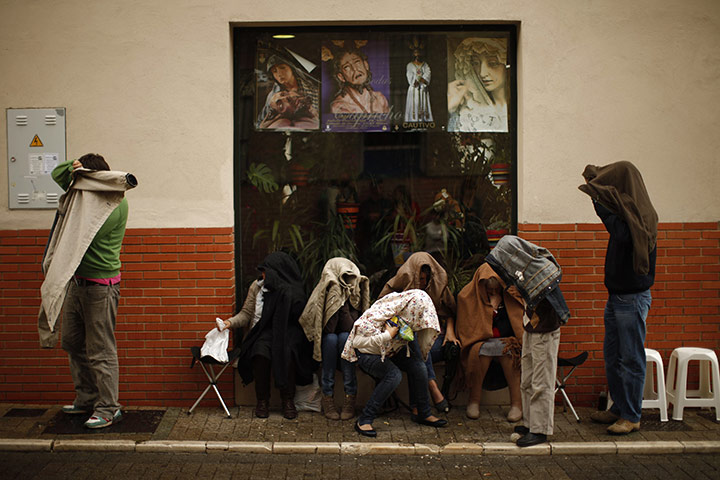 Holy Week in Malaga: People cover up from the rain with their coats