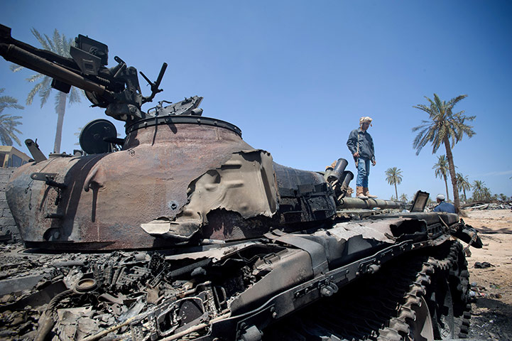 Life in masrata libya: A rebel fighter stands on the burned out carcass of a tank 