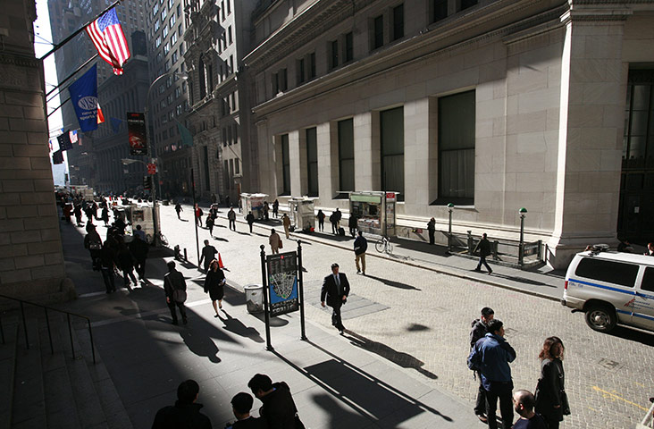 Business Week: People walk along Wall Street