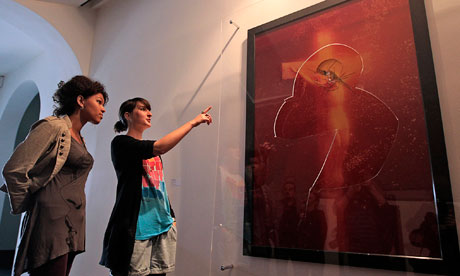 Visitors look at Piss Christ an image of the crucifixion submerged in the 