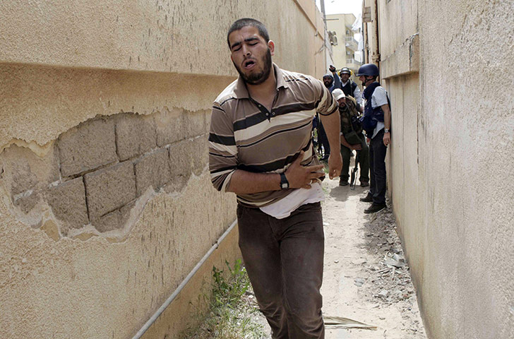 Misrata Libya: A wounded Libyan rebel fighter runs during house-to house fighting