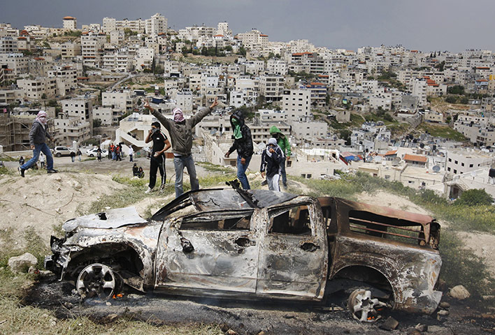 24 Hours: Masked Palestinian youths celebrate near a burnt Israeli army vehicle