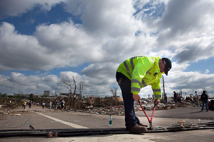 US Tornado: Casey Wallace tries to clear a road of power lines in Tuscaloosa
