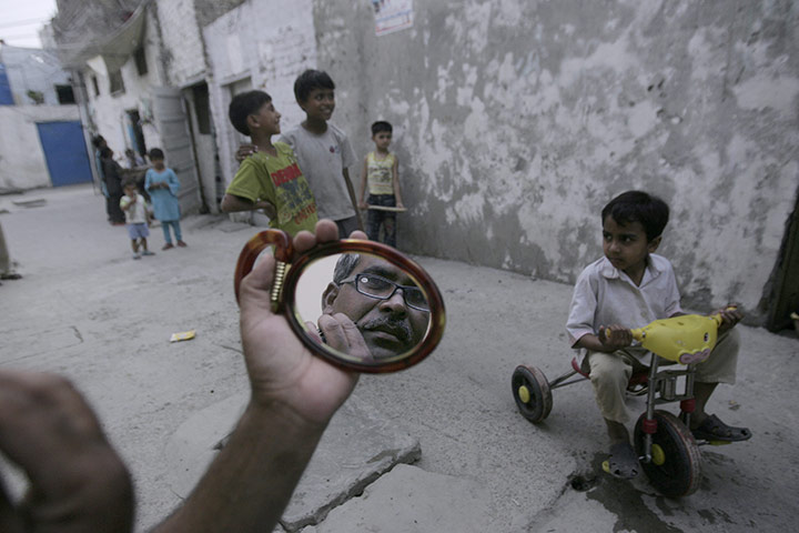 24 hours in pictures: A Pakistani man is reflected in a mirror