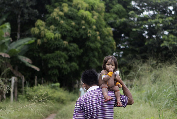 24 hours in pictures: A Kayapo man carries his child  in Sao Felix, Brazil