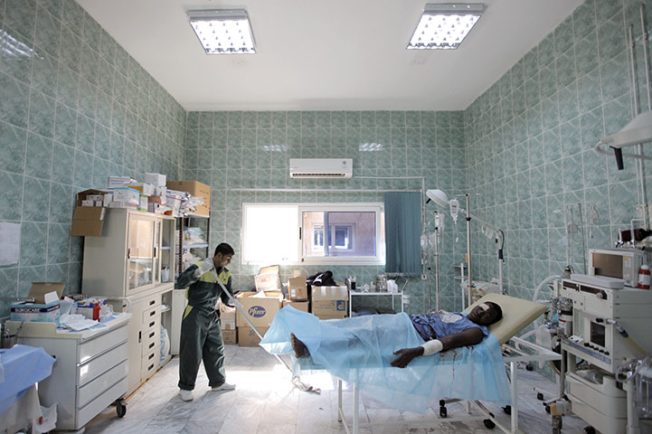 24 hours in pictures: Ajdabiya, Libya: A man cleans the floor next to an injured Libyan youth