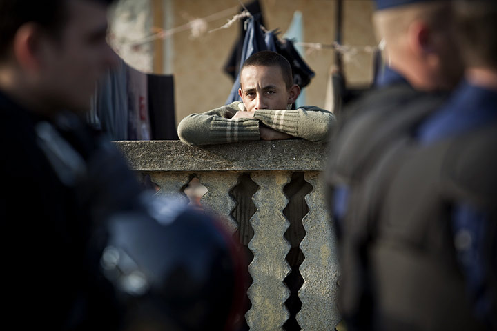 24 hours in pictures: Hejoszalonta, Hungary: A member of the local gypsy community watches police