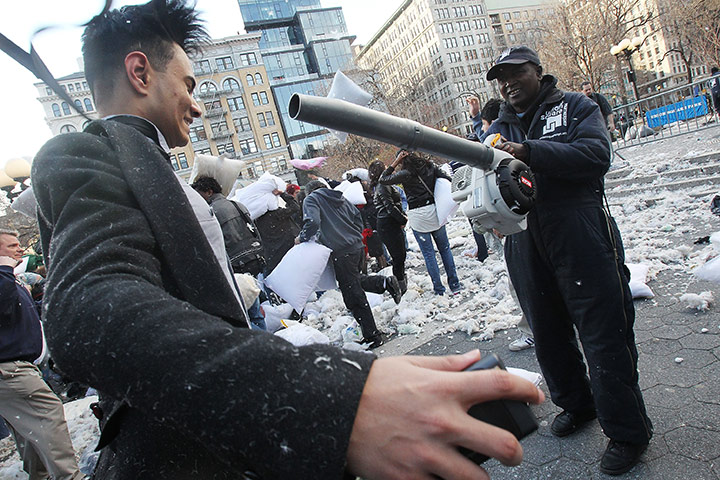 Pillow fight day: New York, USA: A worker uses a leaf blower on a man covered in feathers