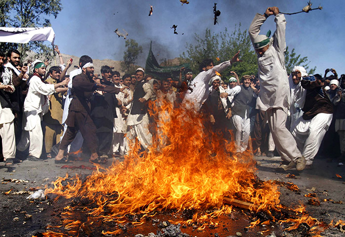 Afghanistan protests: An Afghan protestor beats a burning effigy of President Obama in Jalalabad