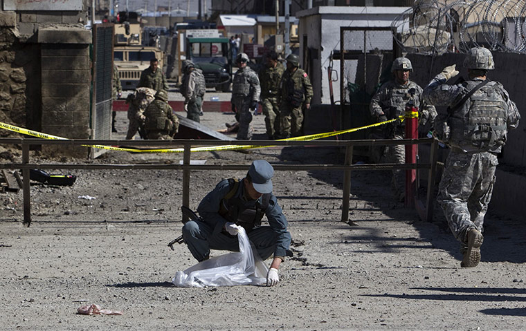 Afghanistan protests: An Afghan policeman collects body parts after an attack at Camp Phoenix