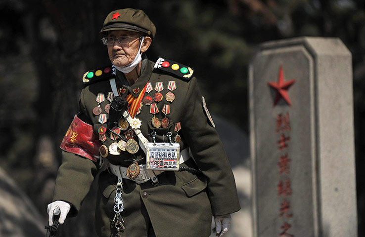 24 hours in pictures: Shenyang, China: A Korean war veteran walks by the grave of fallen soldier