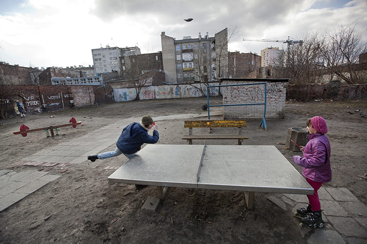 David Levene Poland: Children playing table tennis against a backdrop of old blocks in Praga