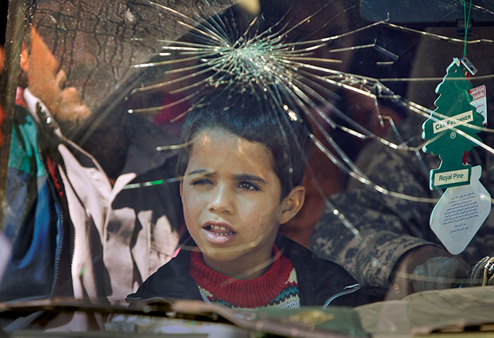 24 hours in pictures: A young boy looks through the damaged windscreen, Libya