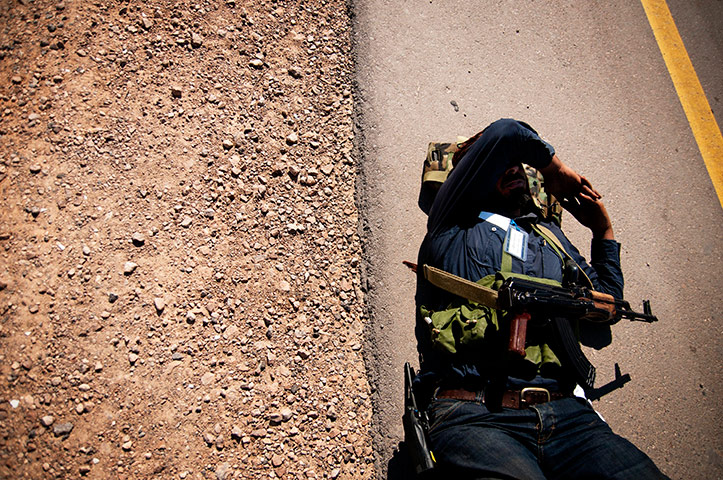 24 hours in pictures: A rebel soldier takes a break on the road, Libya